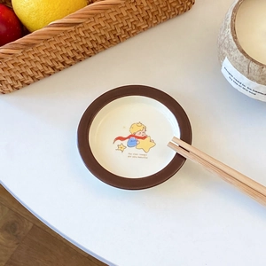 Detail of ceramic Little Prince dish with illustration on white tabletop setting