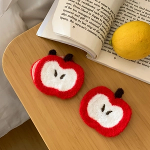 Detailed view of handmade crochet apple patches with red yarn texture and seed details