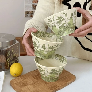 Detail of three stacked ceramic lily of the valley bowls held by hand in a warm kitchen