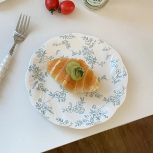 Top view of French vintage floral ceramic plate with blue relief patterns and wavy edges