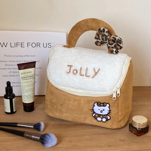 Detail of suede house makeup bag with fluffy flap, jolly embroidery, and leopard bow
