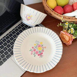 Top view of vintage French floral ceramic bowl and plate set on dark wooden table