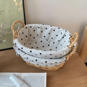 Detail of woven storage basket with dual handles and grey polka dot lining on wood table