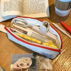 Quilted lattice pencil case with red zipper on wooden desk with stationery