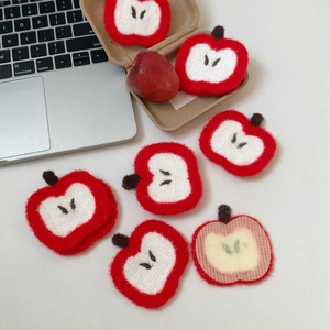 Close-up of cute apple embroidered hair stickers on desk showing textured front and adhesive back