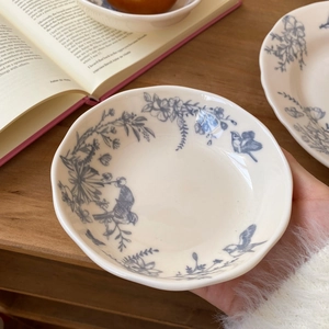 Close-up of French vintage ceramic bowl with blue floral and bird patterns in hand
