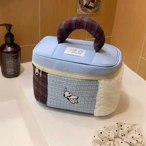 Detail of blue patchwork toiletry bag with cartoon dog embroidery and woven texture