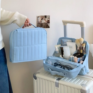 Macro shot of light blue quilted cosmetic bag with multi-layer storage compartments