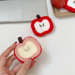 Detail of handmade knit apple hair clip showing the soft texture and velcro backing