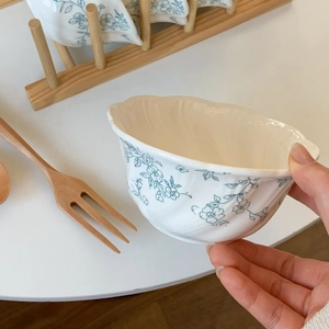 Detail of French vintage ceramic bowl with blue floral relief and wavy edge design