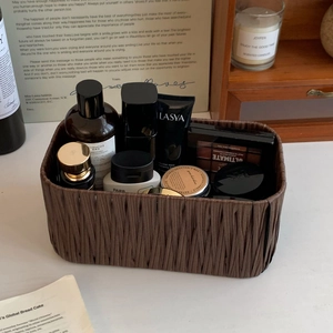 Detail of a brown woven desktop storage basket with skincare products in a warm setting