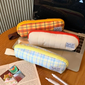 Quilted fabric pencil cases in plaid and solid colors on a desk with a side handle