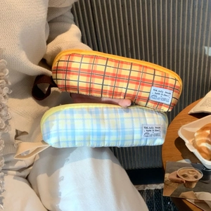 Close-up of portable plaid pencil cases with fabric handles shown in a lifestyle setting