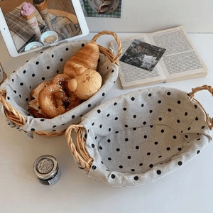 Two-piece set of woven wicker baskets with black and white polka dot liners and handles
