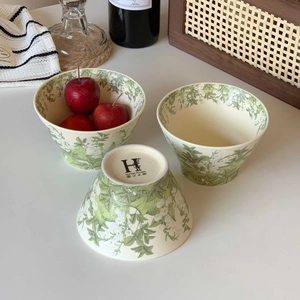 Detailed view of lily of the valley ceramic bowls with floral patterns and brand logo
