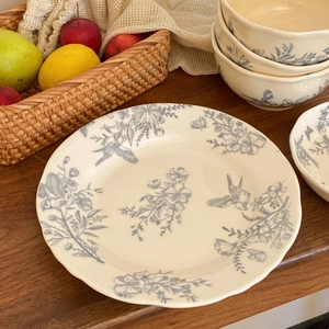 Detail of vintage ceramic plate and bowl with blue floral and bird patterns on wood