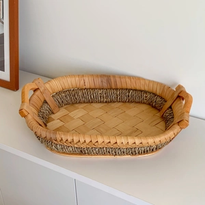 Detailed view of handmade woven oval storage basket with dark grass accents and sturdy handles