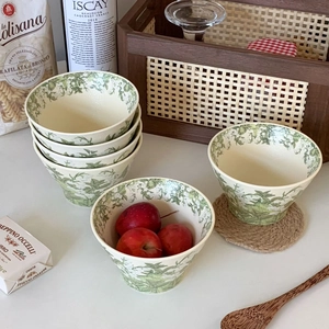 Detail of stacked lily of the valley ceramic bowls with green leaf patterns and high foot
