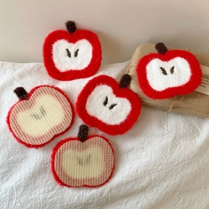 Detail of red apple crochet hair patch showing knit texture and non-slip backing