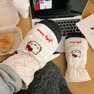 Detail of warm white cat-themed ski mittens with waterproof fabric on a cozy wooden table