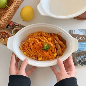 Detailed view of hands holding a white ceramic bowl with handles for salad and pasta