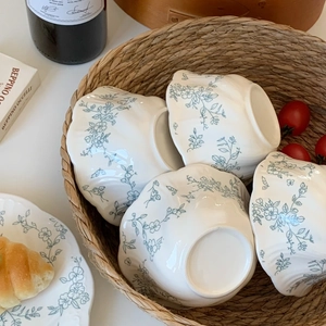 Detail of floral embossed ceramic tableware set with blue patterns in a rustic woven basket
