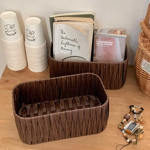 Detail of dark brown woven storage basket with vertical pleated texture on wood desk