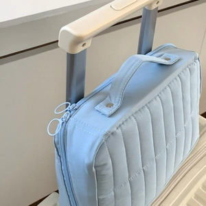 Light blue quilted travel cosmetic bag detail showing the luggage handle strap