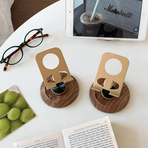 Detail of vintage walnut wood base and gold metal rotating bracket for desktop phone stand