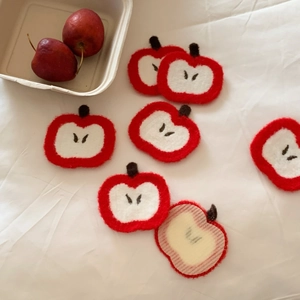 Macro detail of handmade felt apple hair patch with vibrant red and cream wool textures