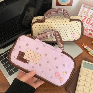 Quilted cotton pencil cases with grid handles and embroidery in a warm workspace setting