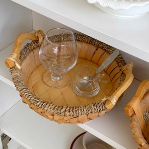 Detailed texture of hand-woven rattan tray with hemp rope handles on white shelf