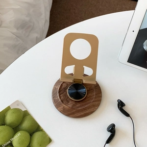 Detail of a desktop folding stand with a wood grain base and matte gold metal finish