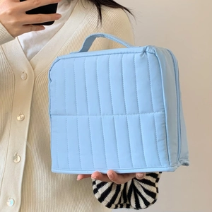 Close-up of a blue quilted cosmetic bag with a handle and zipper for travel storage