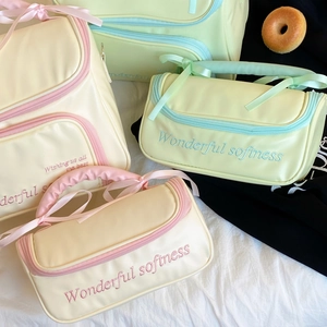 Détail de la trousse de toilette avec poignée en nœud et broderie décorative
