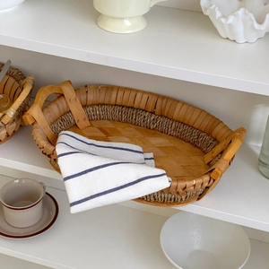 Detail of hand-woven oval storage basket with blue striped fabric lining and dual handles