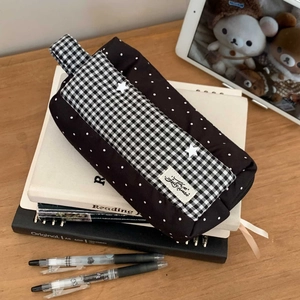 Vue de dessus d'une trousse à grande capacité avec motifs vichy noirs et pois sur bureau