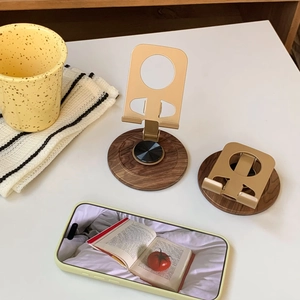 Detail of a foldable metal phone stand with a vintage walnut wood base and non-slip pads
