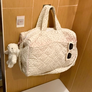 Detail of beige quilted floral tote bag with plush bunny charm and side pocket