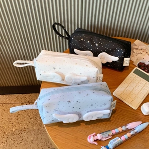 Detail view of star pattern pencil cases with plush wings in black, white and blue