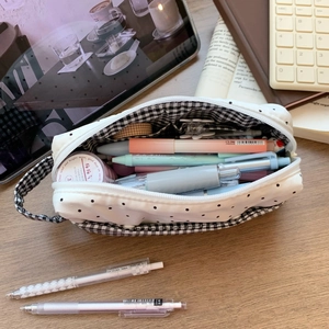Vue détaillée du plumier blanc à pois contenant des stylos et du ruban washi sur bureau
