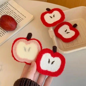 Close-up of cute red apple plush hair clip accessories with soft heart-shaped details