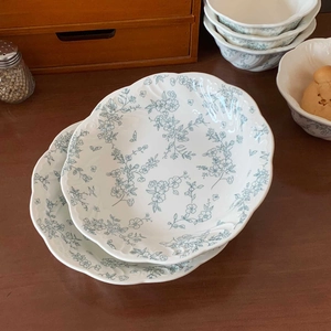 Detail of vintage French ceramic plates featuring light blue floral patterns and scalloped edges