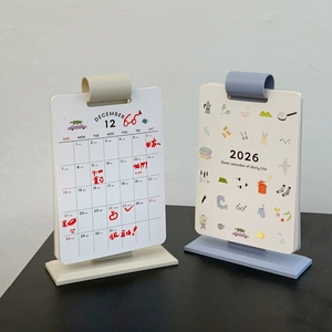 Detail of 2026 desk calendar with beige and blue L-shaped stands and round clips