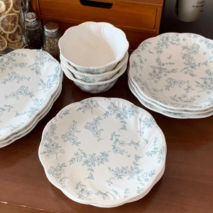 Stacked French vintage ceramic tableware set with blue floral relief and wavy edges