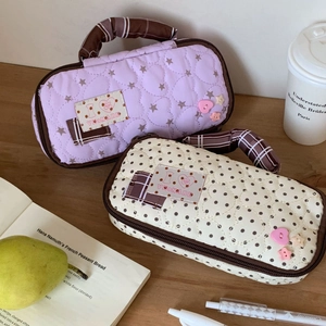 Quilted pencil case detail with heart stitching, checked handles and brand label