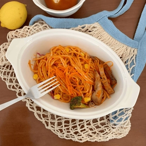 Oval white ceramic baking dish with handles featuring tomato pasta on a wooden table