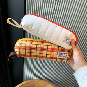 Detail of quilted white and orange plaid pencil cases with handheld carry straps
