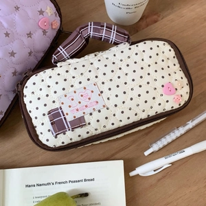 Detailed close-up of a quilted dot pencil case with a heart charm and plaid handle