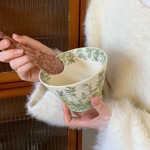 Close-up of hands holding lily of the valley ceramic bowl with a wooden spoon